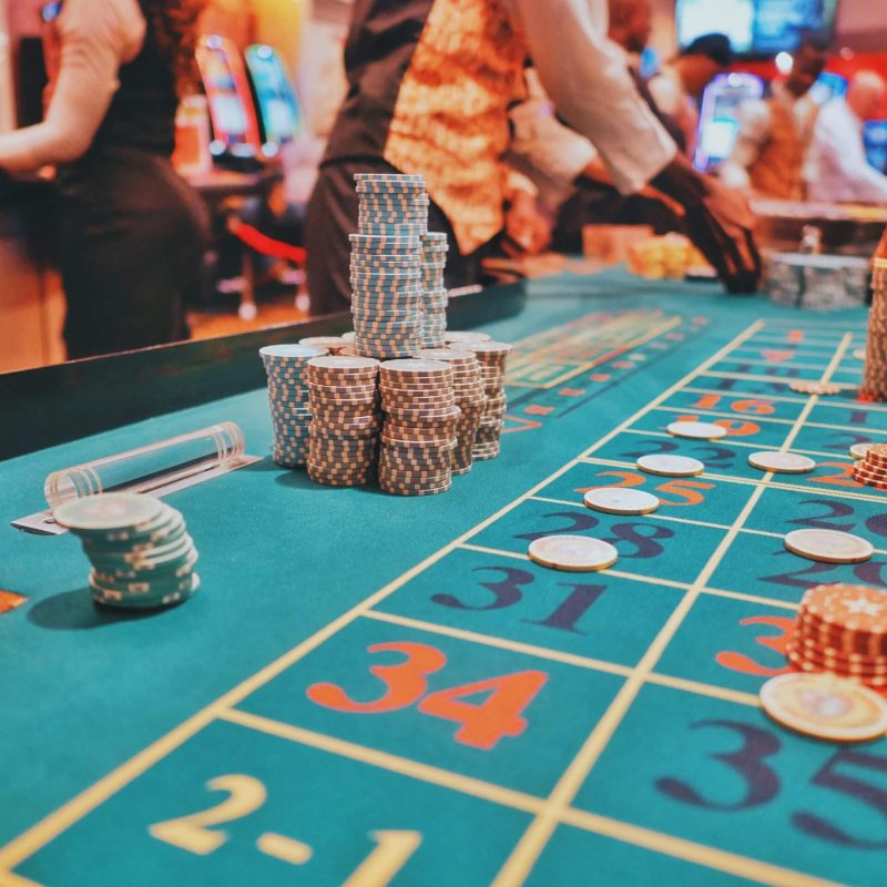 Casino roulette table with chips and croupiers.